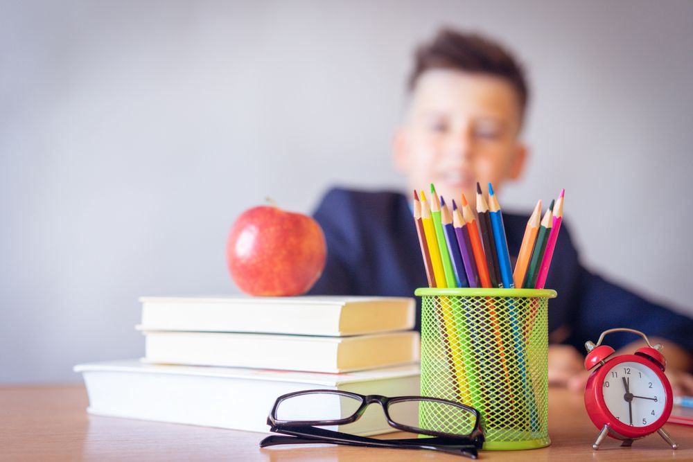 Books, an apple, and pencils on a desk
